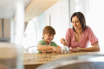 Mother and daughter filling piggy bank