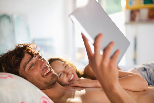 Couple using tablet computer in bed