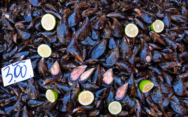 Black, mottled mussels on the counter of a street market