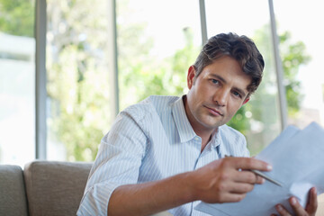 Businessman reading papers on sofa