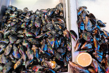 Black, mottled mussels on the counter of a street market