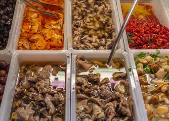 Salted and pickled mushrooms in store counter containers