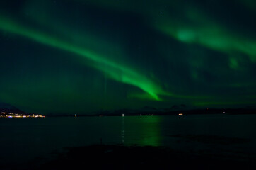 aurora borealis over fjord and mountain range