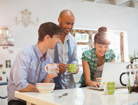 Friends using laptop together at breakfast