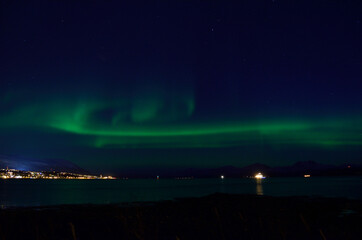 beautiful aurora borealis over fjord and land in tromsoe
