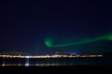 Naklejka na ściany i meble beautiful aurora borealis over fjord and land in tromsoe