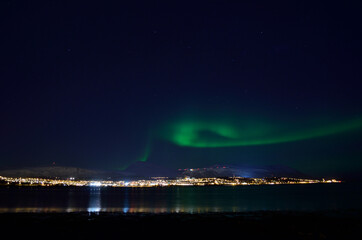 Naklejka na ściany i meble beautiful aurora borealis over fjord and land in tromsoe