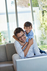 Father and son using laptop on sofa