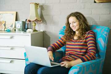 Woman using laptop in armchair