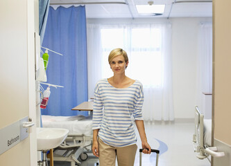 Patient wheeling luggage out of hospital room