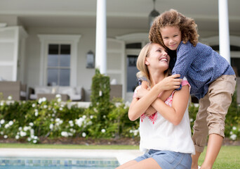 Mother and daughter hugging by swimming pool