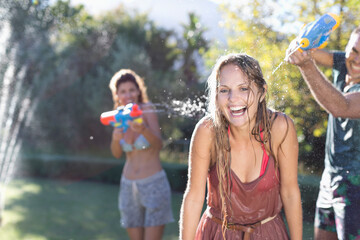 Friends playing with water guns in backyard