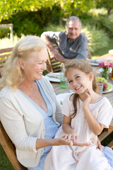 Older woman sitting with granddaughter outdoors