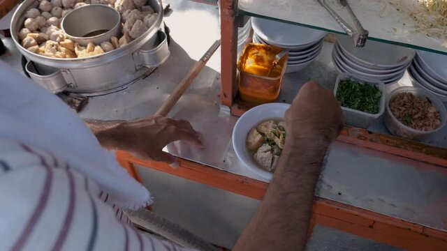 bakso. indonesian famous meatball street food vendor close up hand serving