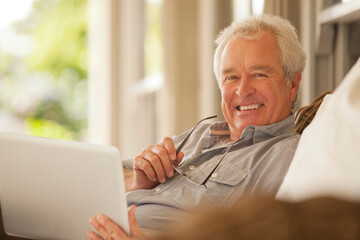 Portrait of smiling senior man using laptop on porch