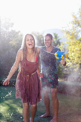 Couple playing with water guns in backyard