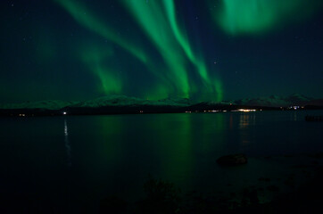 Naklejka na ściany i meble incredible strong aurora borealis over fjord and snowy mountain