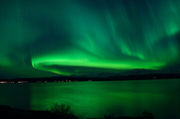 Naklejka na ściany i meble insanly strong aurora borealis over arctic fjord and mountain landscape