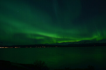 Fototapeta na wymiar insanly strong aurora borealis over arctic fjord and mountain landscape