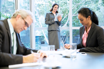 Smiling woman using digital tablet at window in conference room