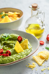 Homemade guacamole with nachos, chilli peppers and coriander