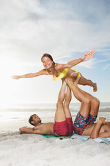 Men lifting woman with legs on beach
