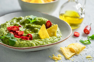Traditional guacamole with nachos, chilli peppers and coriander