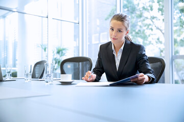 Portrait serious businesswoman reviewing paperwork in conference room