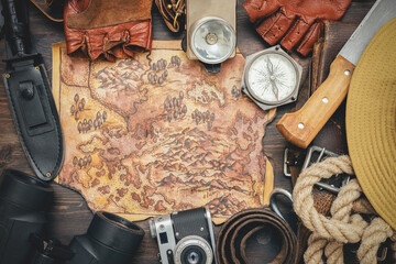 Old treasure map and adventurer equipment on the old table background.