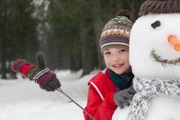 Close up of smiling boy behind snowman