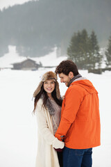 Fototapeta premium Happy couple holding hands in snowy field