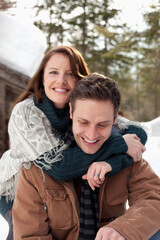 Obraz premium Portrait of hugging couple outside snowy cabin