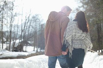 Couple holding hands and walking in snowy lane