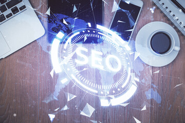 Double exposure of SEO hologram drawing over desktop. Top view. Search optimization concept.