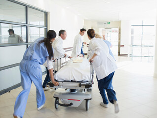 Doctors rushing patient on stretcher down hospital corridor