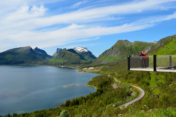 tourists on lookout point, senja with blue sky and fjord landscape