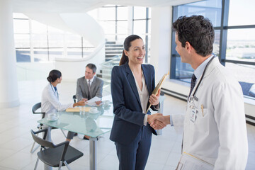 Doctor and businesswoman handshaking in meeting - Powered by Adobe