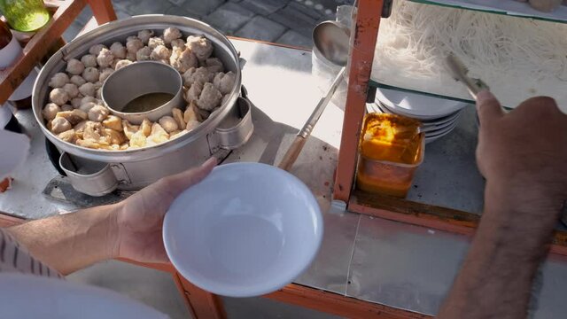 bakso. indonesian famous meatball street food vendor close up hand serving