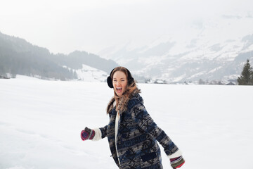 Fototapeta na wymiar Portrait of enthusiastic woman running in snowy field
