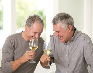 Senior men laughing and drinking white wine