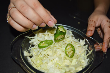 young woman decorating salad isolated on dark background, japanese woman decorating with hand on dark background. food and drink.