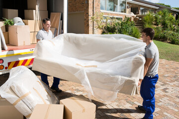 Movers carrying sofa from moving van in driveway