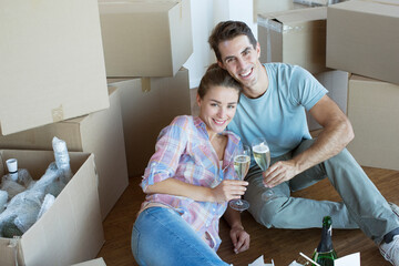 Portrait of couple enjoying champagne among cardboard boxes