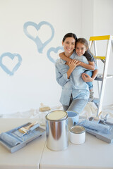 Mother and daughter hugging among paint supplies - obrazy, fototapety, plakaty