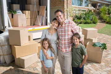 Portrait of smiling family standing near moving van in driveway