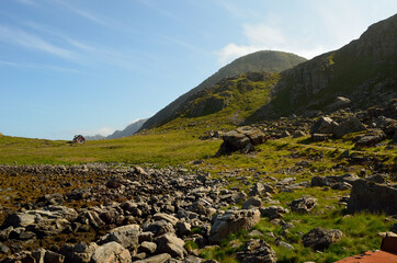 little red lonely cabin next to tall mountain and seashore
