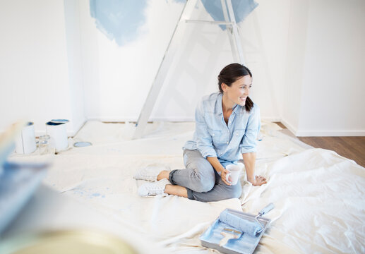 Woman drinking coffee surrounded by painting supplies