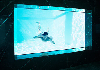 Man looking through window underwater in swimming pool