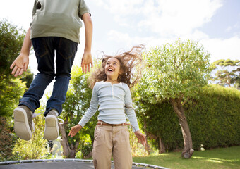Children jumping on trampoline in backyard