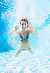 Obraz na płótnie Canvas Woman giving thumbs up underwater in swimming pool